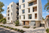 Modern apartment building with sleek design, featuring spacious balconies and abundant natural light, surrounded by lush landscaping.