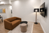 Cozy modern living room with a stylish brown sofa, elegant floor lamp, and wall-mounted flat-screen TV, perfect for relaxation.