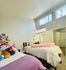 Inviting bedroom featuring two twin beds adorned with plush stuffed toys, bright natural lighting, and modern decor.