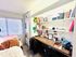 Inviting small bedroom with a well-organized study area, featuring a built-in desk and shelves filled with books.