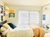 Charming bedroom with modern decor, featuring a comfy bed, artistic wall art, and large windows letting in natural light.