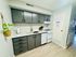 Sleek kitchen with dark cabinetry, stainless steel sink, and modern appliances.