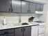 Modern kitchen with gray cabinetry, marbled countertops, and stainless steel fixtures.