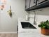 Sleek modern kitchen with marble countertops, stylish faucet, and hanging plant decor.