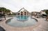 Luxurious resort-style swimming pool with elegant loungers and umbrellas, surrounded by charming architecture and lush palm trees.