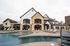 Luxurious residential complex with a charming stone facade, featuring a sparkling swimming pool, sun loungers, and a spacious outdoor seating area.