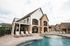 Charming residential building with a stone façade and spacious deck overlooking a pristine pool and stylish poolside seating.