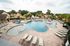 Inviting community pool surrounded by elegant lounge chairs and lush greenery, perfect for relaxation and entertainment.