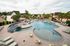 Inviting community pool area with elegant lounge chairs, shaded seating, and lush palm surroundings, perfect for relaxation and leisure.