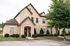 Charming stone-accented townhouse with lush greenery and inviting front entrance.