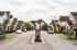 Inviting suburban community with charming stone houses, lush greenery, and serene streetscape ideal for tranquil living.