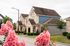 Charming suburban homes with elegant stone facades and lush pink flowers, perfect for modern living.