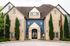 Elegant entrance of a charming stone leasing office with lush greenery and classic architecture.