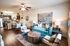 Bright and inviting living area featuring a modern open-plan design with a chic teal sofa, stylish wooden centerpiece, and a functional kitchen layout.