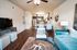 Modern living room with elegant decor, featuring a plush teal sofa, stylish wooden coffee table, and open dining area leading to a contemporary kitchen with stainless steel appliances.