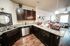 Chic open-plan kitchen with granite countertops, modern appliances, and elegant lighting leading into a cozy living area.