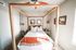 Inviting bedroom featuring a stylish four-poster bed, cozy linens, and modern art, perfect for relaxation.