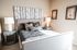 Chic modern bedroom featuring a stylish gray bed with a unique forest-themed headboard, cozy pillows, and elegant lamps creating a serene ambiance.