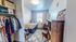 Cozy bedroom with vibrant decor, featuring an organized open closet, stylish study area, and ample natural light.
