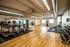 Spacious and modern gym with state-of-the-art exercise equipment, wooden flooring, and ample natural light.