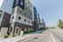 Modern apartment complex with a sleek design and diverse color palette, located along a spacious street with vibrant greenery.