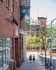 Charming urban scene featuring historic brick architecture, vibrant greenery, and a lively street with pedestrians.