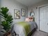 Charming bedroom with vibrant decor, elegant plant, and modern wall art creating a serene and inviting space.
