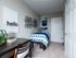 Cozy bedroom with modern decor, featuring a single bed with geometric bedding, a stylish desk setup, and an inviting artwork display.