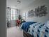 Chic bedroom with modern decor, featuring a comfortable bed with geometric bedding, a stylish desk with a vibrant chair, and artistic wall accents.