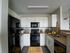 Modern kitchen with sleek black appliances, elegant white cabinetry, and stylish countertop decor.