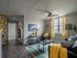 Modern apartment living room with vibrant yellow accents, cozy seating, large window, and stylish decor.
