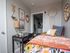 Charming bedroom showcasing vibrant decor, cozy bedding, and stylish wall art with a tranquil workspace.