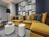 Contemporary living room with vibrant mustard sofas, geometric wall art, and stylish round coffee tables.
