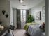 Charming bedroom with a stylish decor, featuring striped bedding, vibrant plant accents, and natural light from a large window.