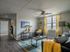 Bright and inviting living room with modern decor and large window, featuring cozy seating, stylish artwork, and vibrant yellow accents.