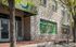 Charming storefront with large windows under a green awning, offering vibrant views on a sunny day.