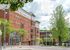Charming urban apartment building with classic red brick architecture and lush green surroundings, perfect for modern living.