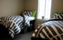 Cozy bedroom with two twin beds adorned in modern patterned bedding, complemented by soft natural light through a large window.