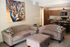 Inviting open-concept living room with plush seating, chic kitchen, and elegant peacock artwork.