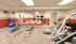 Modern apartment gym featuring state-of-the-art fitness equipment, mirrors, and ample natural light for an invigorating workout experience.