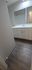 Modern bathroom with sleek white vanity, ample storage, and elegant wood flooring, offering a refreshing, stylish appeal.