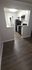 Modern kitchen with sleek black appliances, elegant white cabinetry, and rich wood flooring, creating a stylish and inviting cooking space.