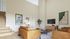 Elegant living room with high ceilings, cozy leather sofas, modern art pieces, and a sleek staircase for a luxurious atmosphere.