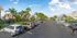 Vibrant community parking area surrounded by lush greenery and stylish townhomes under a clear blue sky, offering a welcoming and serene atmosphere.