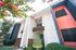 Vibrant modern apartment exterior with colorful accents and lush greenery under a clear blue sky.