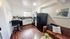 Cozy and stylish kitchen and living area with warm wood flooring, sleek black appliances, chic artwork, and inviting decor.