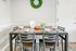 Charming dining area featuring a modern table set with bowls, green apples, and pastries, accented by a decorative wall wreath.