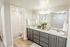 Elegant bathroom featuring dual sinks, sleek grey cabinetry, and contemporary lighting with a fresh floral arrangement.