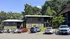 Charming residential apartment buildings surrounded by lush greenery, featuring ample parking space under a clear blue sky.
