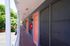 Charming apartment corridor with vibrant orange doors and lush green views, offering a welcoming entrance.